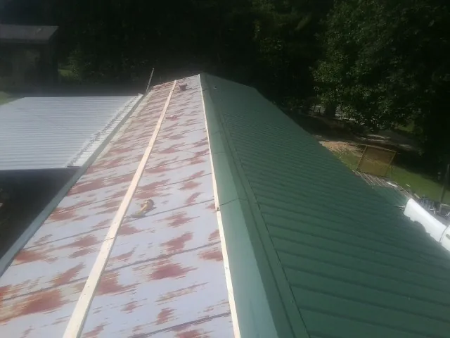 Old rusted panels beside newly installed green metal roofing — Wind Damage Roof Repair by Roofing Brothers in Snyder
