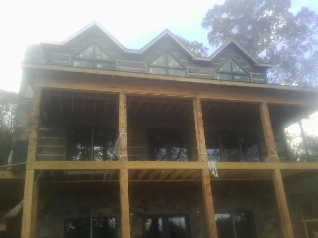 Dormers and porch framing on a large log home under construction — Roof Coating work by our crew in Snyder